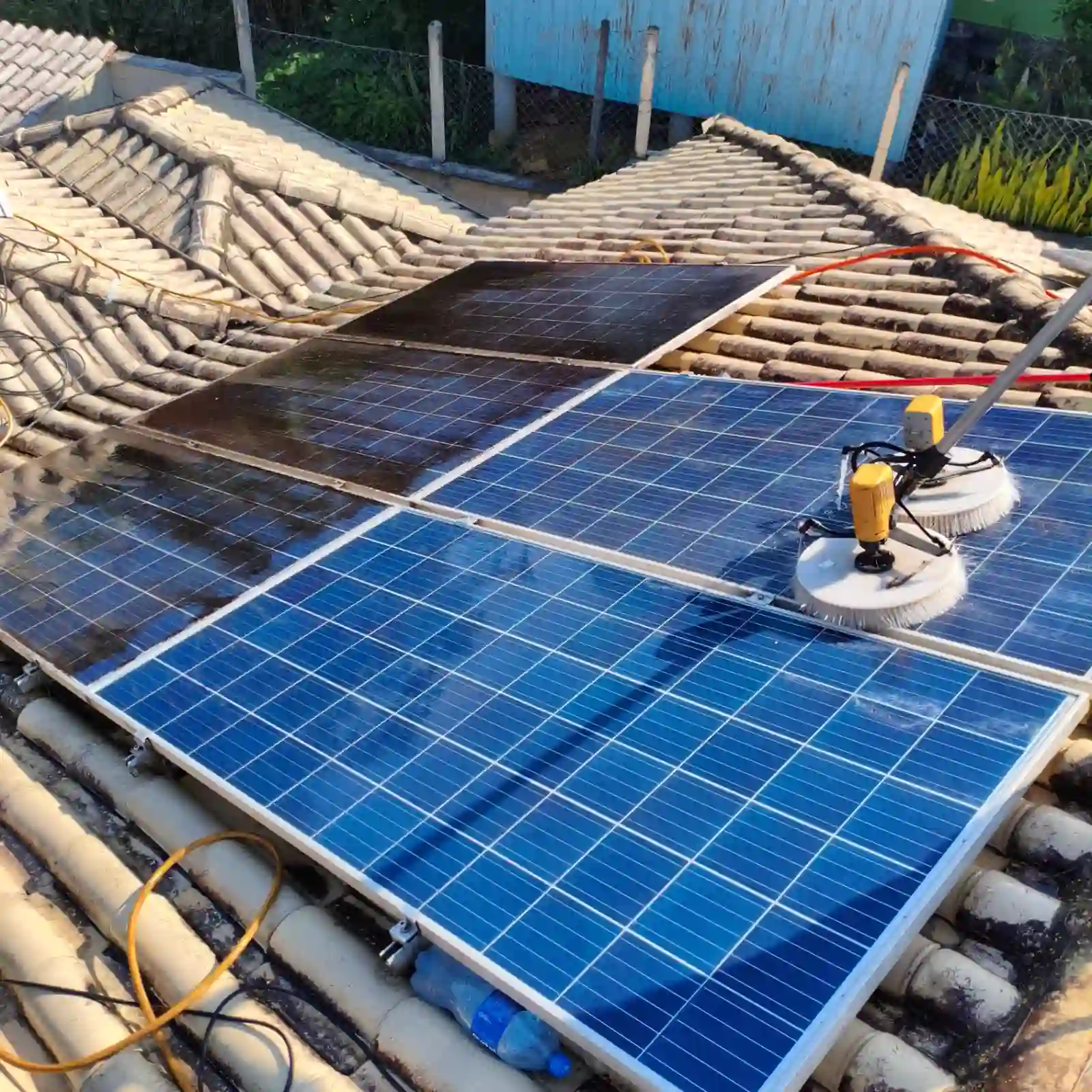 Técnico da Solare Clean limpando painéis solares em telhado com escova rotativa